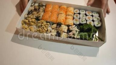 服务员把装满各种日本寿司的盒子<strong>拿来</strong>。 双手正在靠近镜头移动寿司